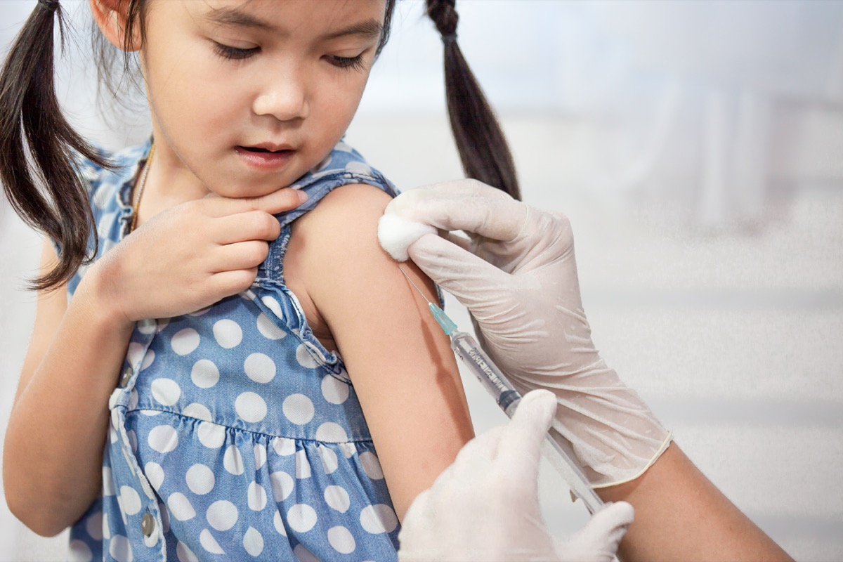 Doctor injecting vaccination in arm of asian little child girl