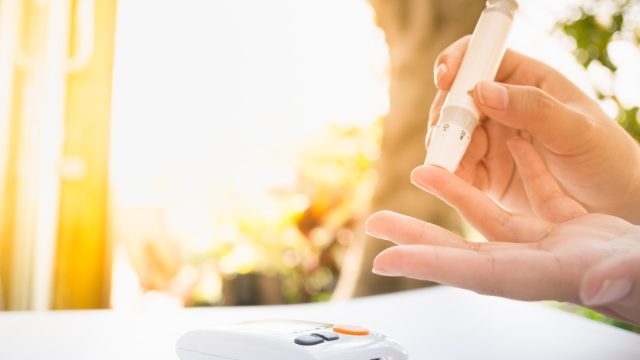 female using lancelet on finger to checking blood sugar level by Glucose meter