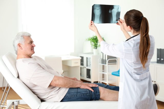 doctor with X-ray and senior patient in clinic. Knee problem