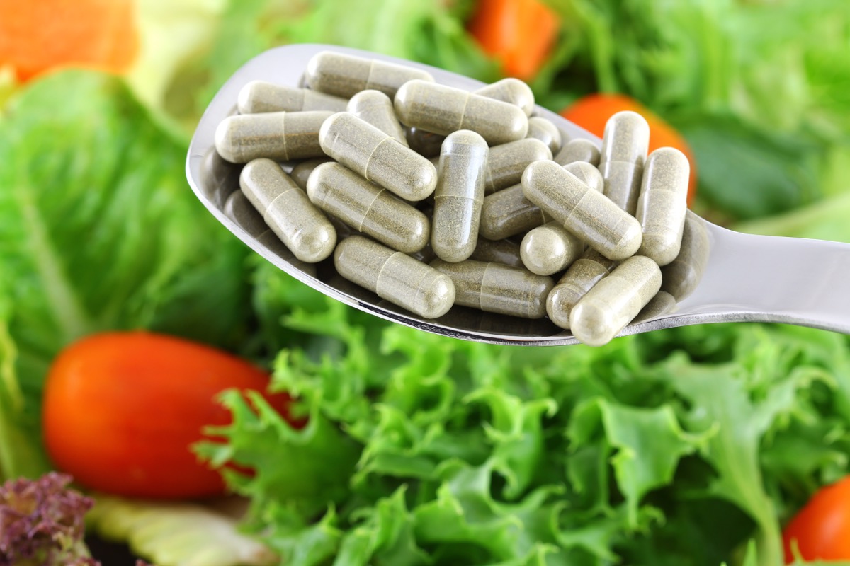 A spoon of concentrated Fiber Capsules with Fresh vegetable Salad background