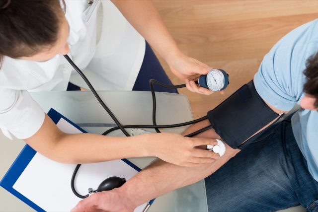 Doctor checking male patient's blood pressure