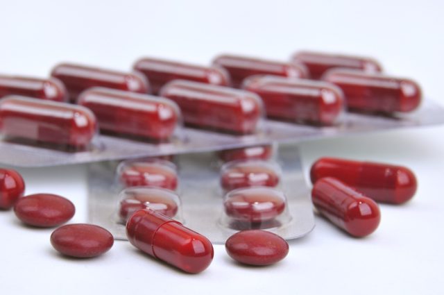 an assortment of red pills and iron supplement capsules