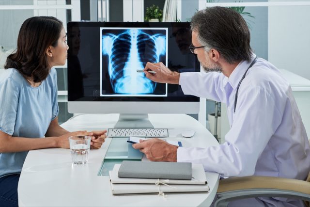 Doctor explaining lungs x-ray on computer screen to patient