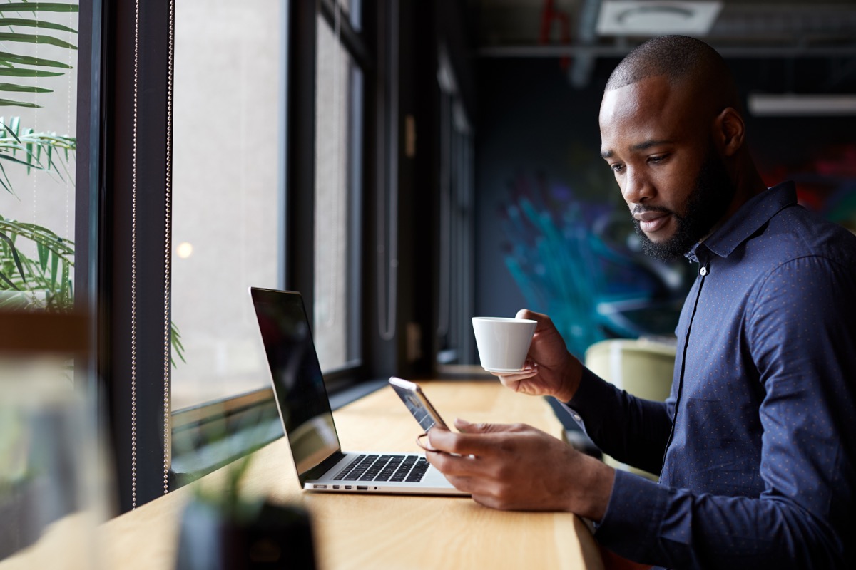 male creative sits by window having coffee