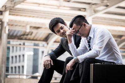 Frustrated Asian young business man sitting outdoor office