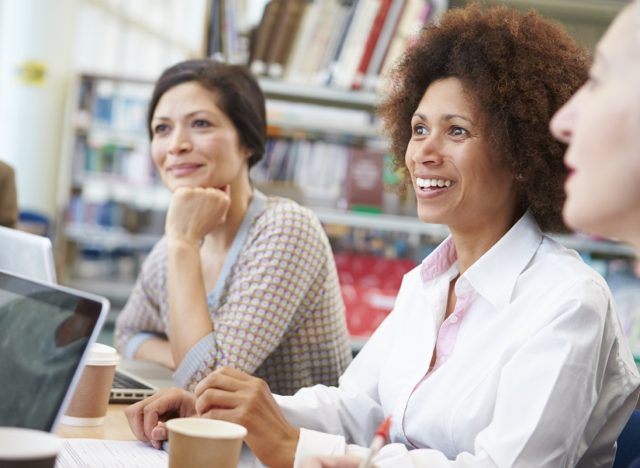 Group Of Mature Students Collaborating On Project In Library
