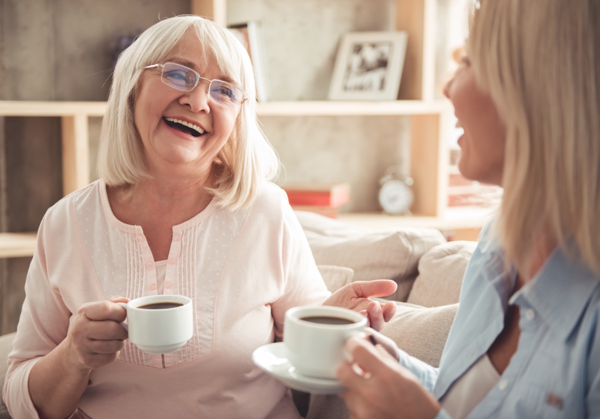 mature mother and her adult daughter are drinking coffee