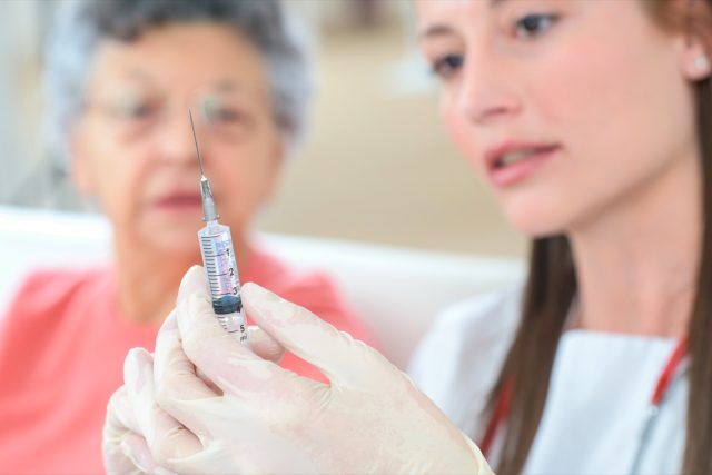 Doctor vaccinating mature woman patient.