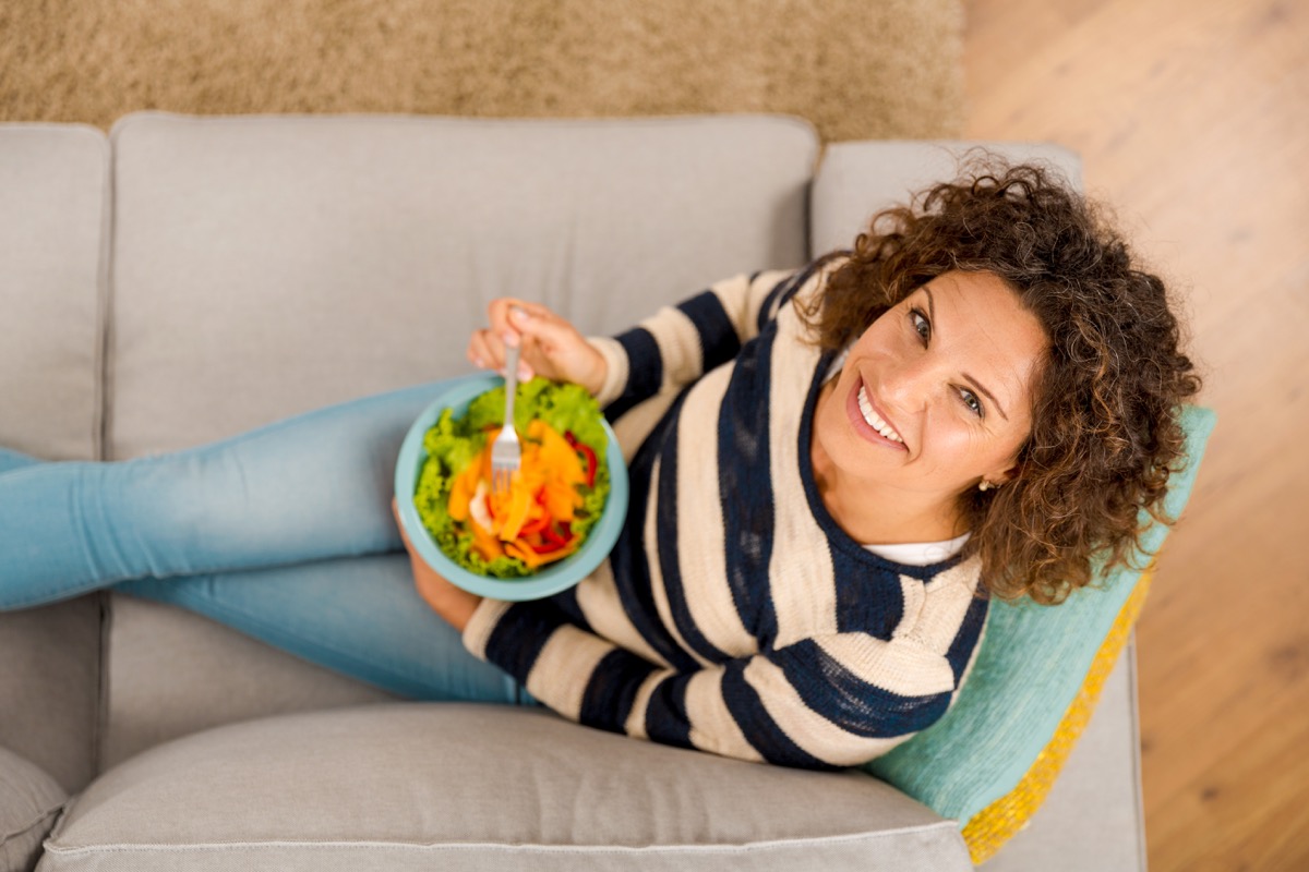 woman on the sofa eating a healthy salad