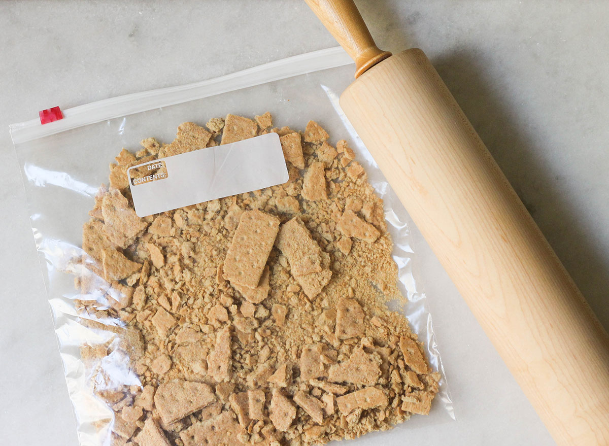 Graham crackers being crushed in a bag with a rolling pin