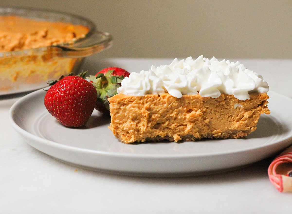 Slice of healthy pumpkin cheesecake with cream and strawberries