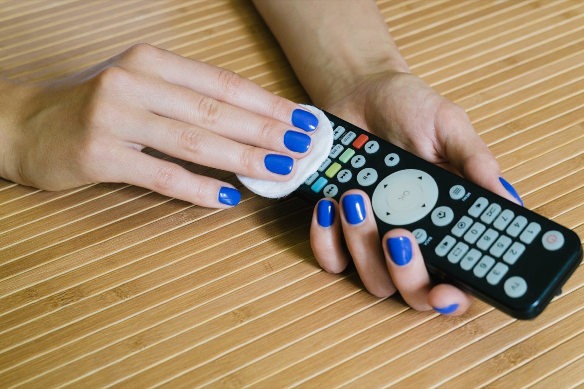 Female hands with blue manicure wipe the remote control