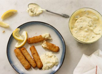 Tartar sauce with fish sticks and lemon wedges on a plate