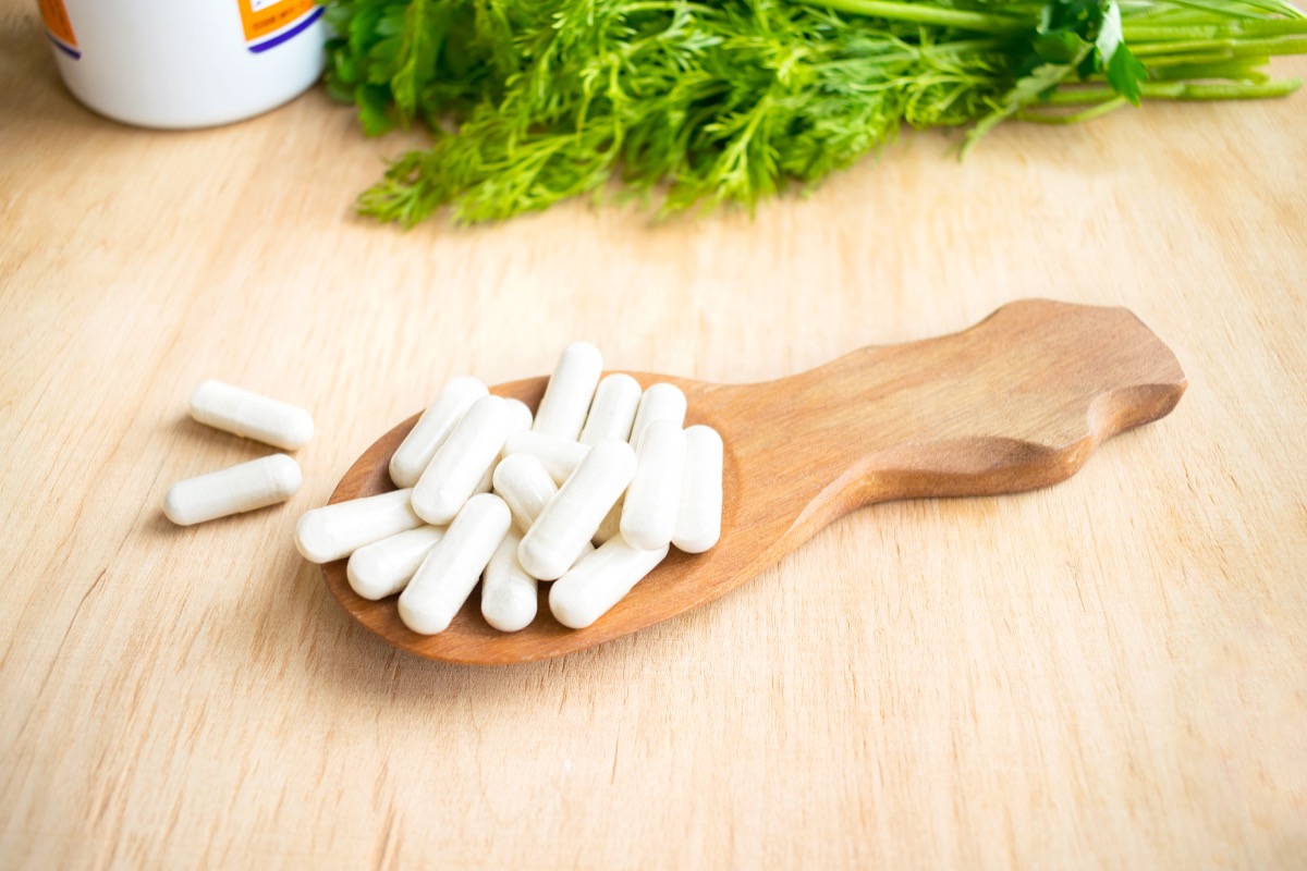 white capsules of vitamin K (phylloquinone) in wooden spoon