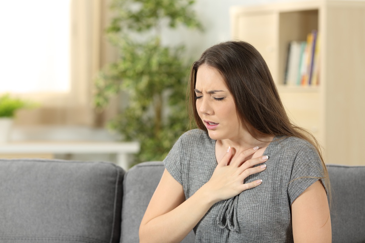 Woman suffering respiration problems sitting on a couch in the living room at home
