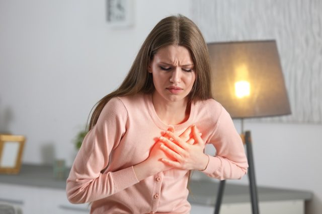 Woman suffering from chest pain indoor