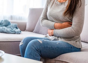 woman with stomach ache sitting on sofa