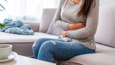 woman with stomach ache sitting on sofa