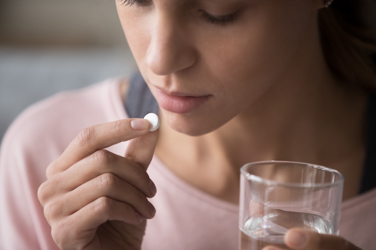 Woman holding pill and glass of fresh water, taking medicine