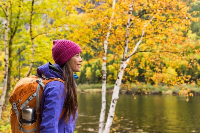 Woman hiker hiking looking at scenic view of fall foliage mountain landscape