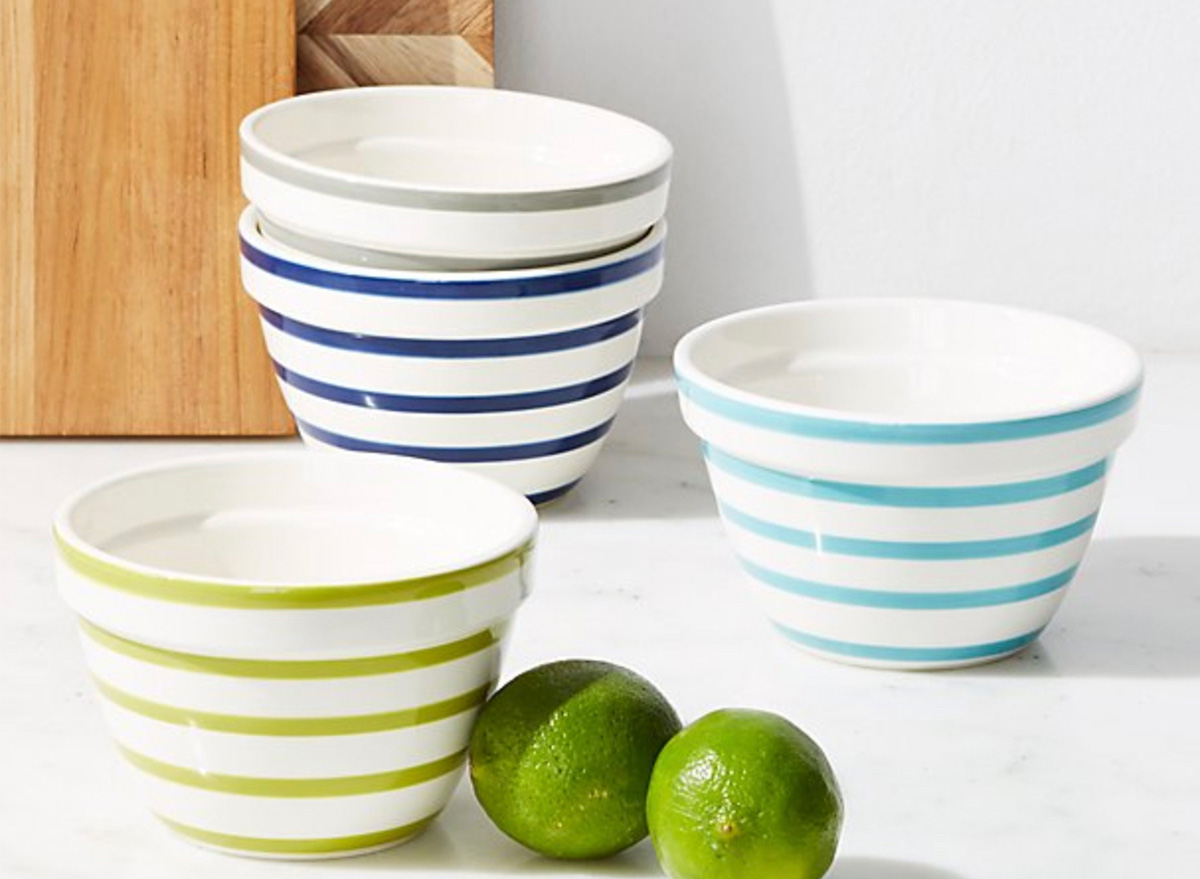 blue and green striped mixing bowls on white counter with two limes