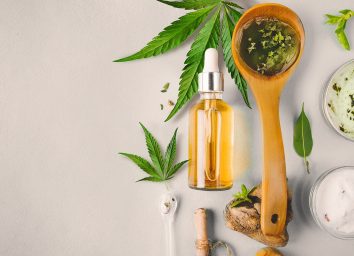 CBD oils in wooden spoon and glass bottle