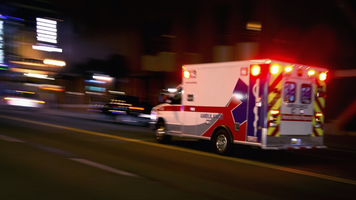 An ambulance speeding through traffic at nighttime