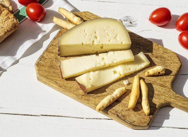 Asiago cheese sliced ​​on a board with crackers and cherry tomatoes