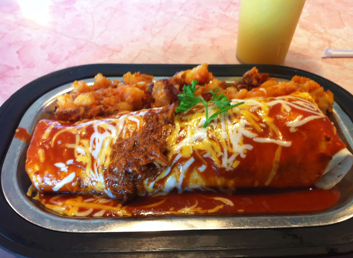 breakfast burrito covered in sauce and cheese with a side of hash browns from pantry restaurant