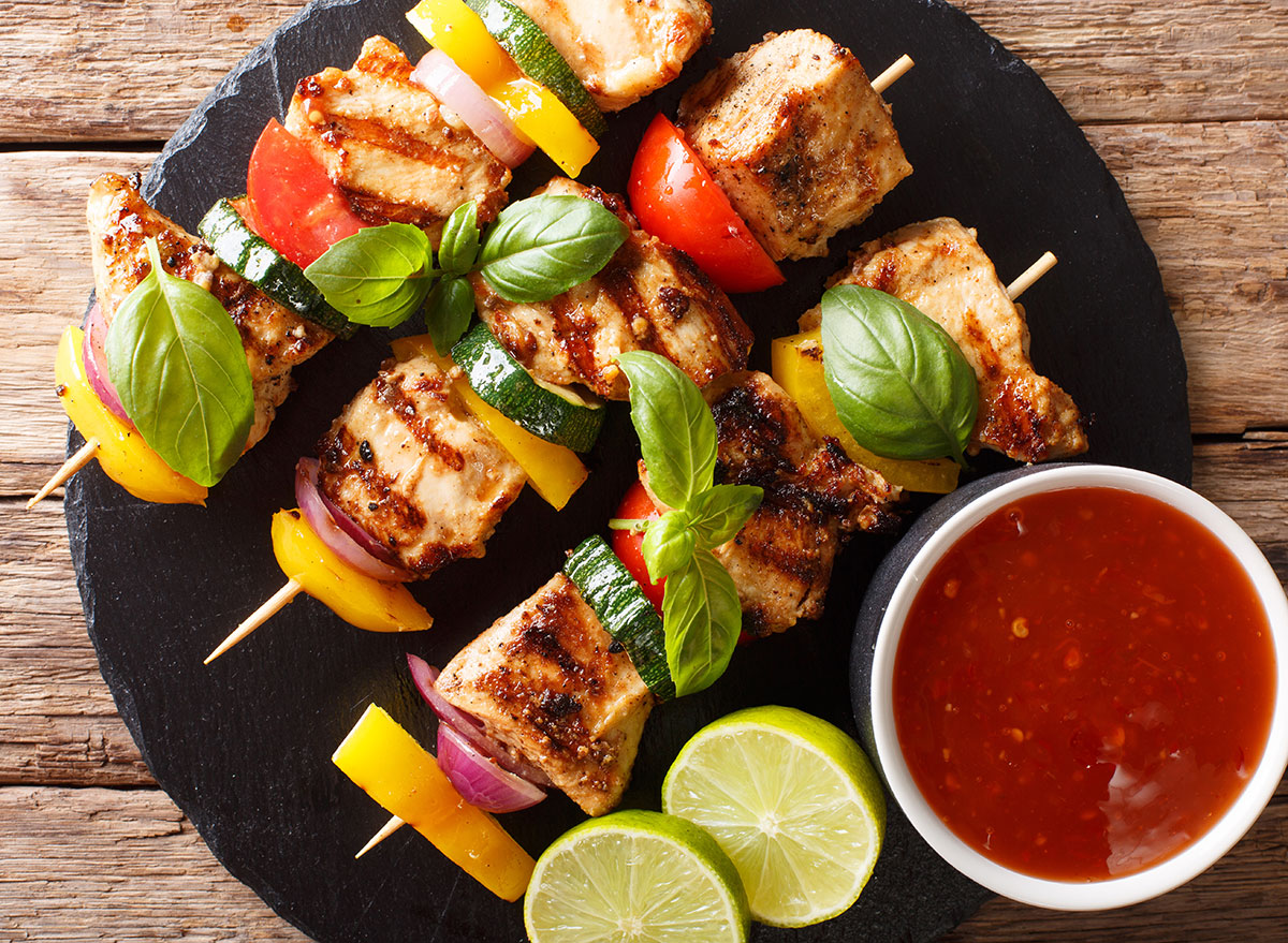 Chicken skewers on a round plate with salsa and limes