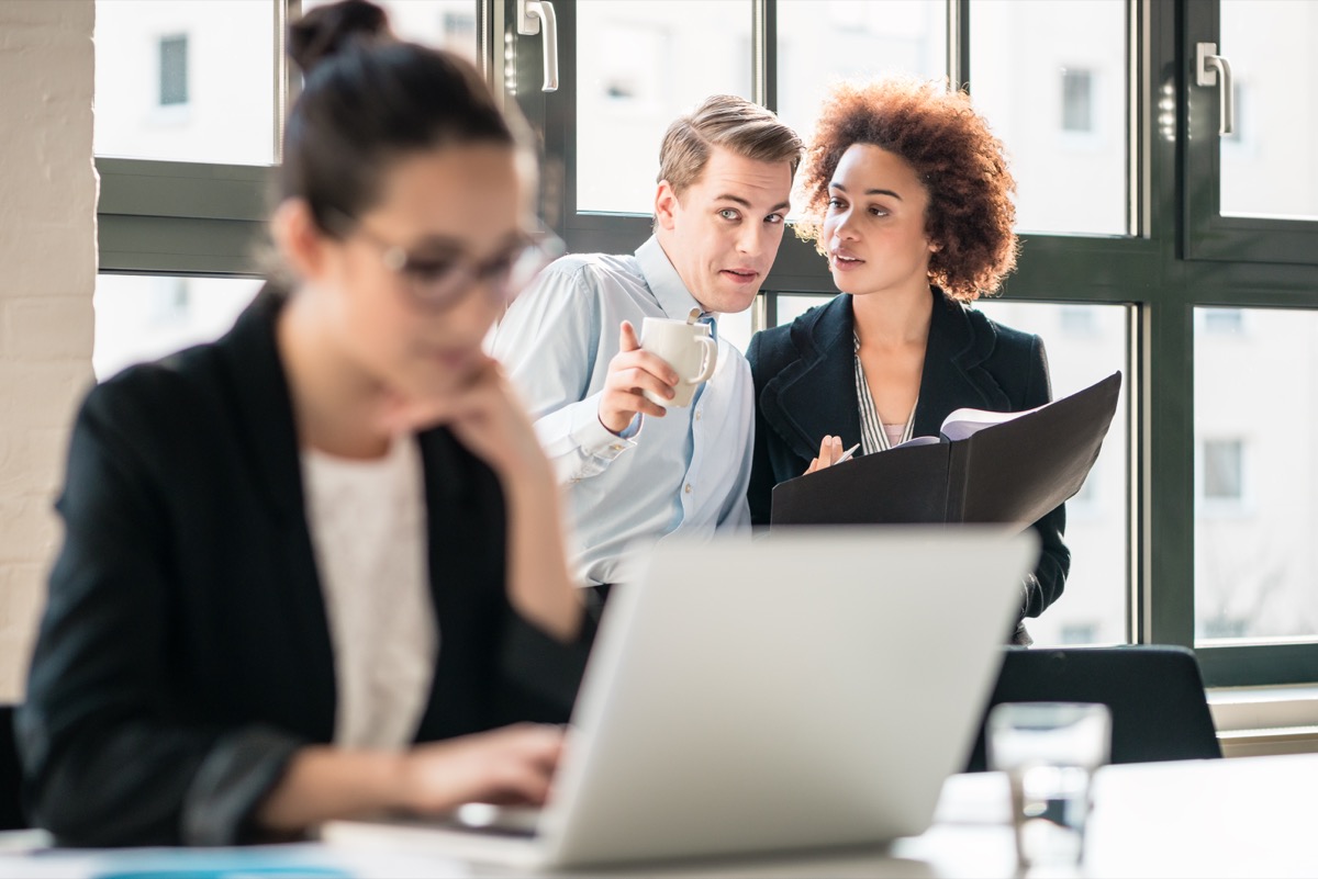 employees gossiping about their hard-working colleague in the office