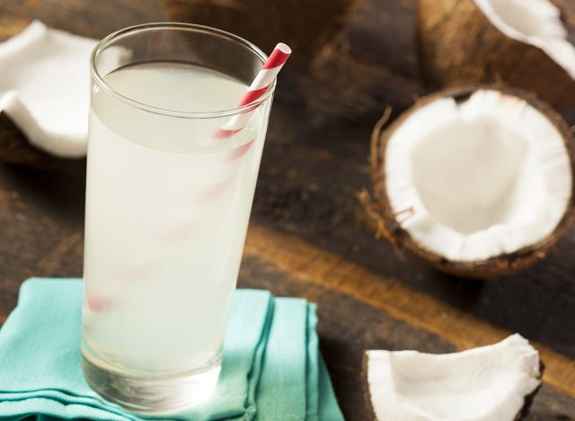 coconut water in a glass surrounded by slices coconuts