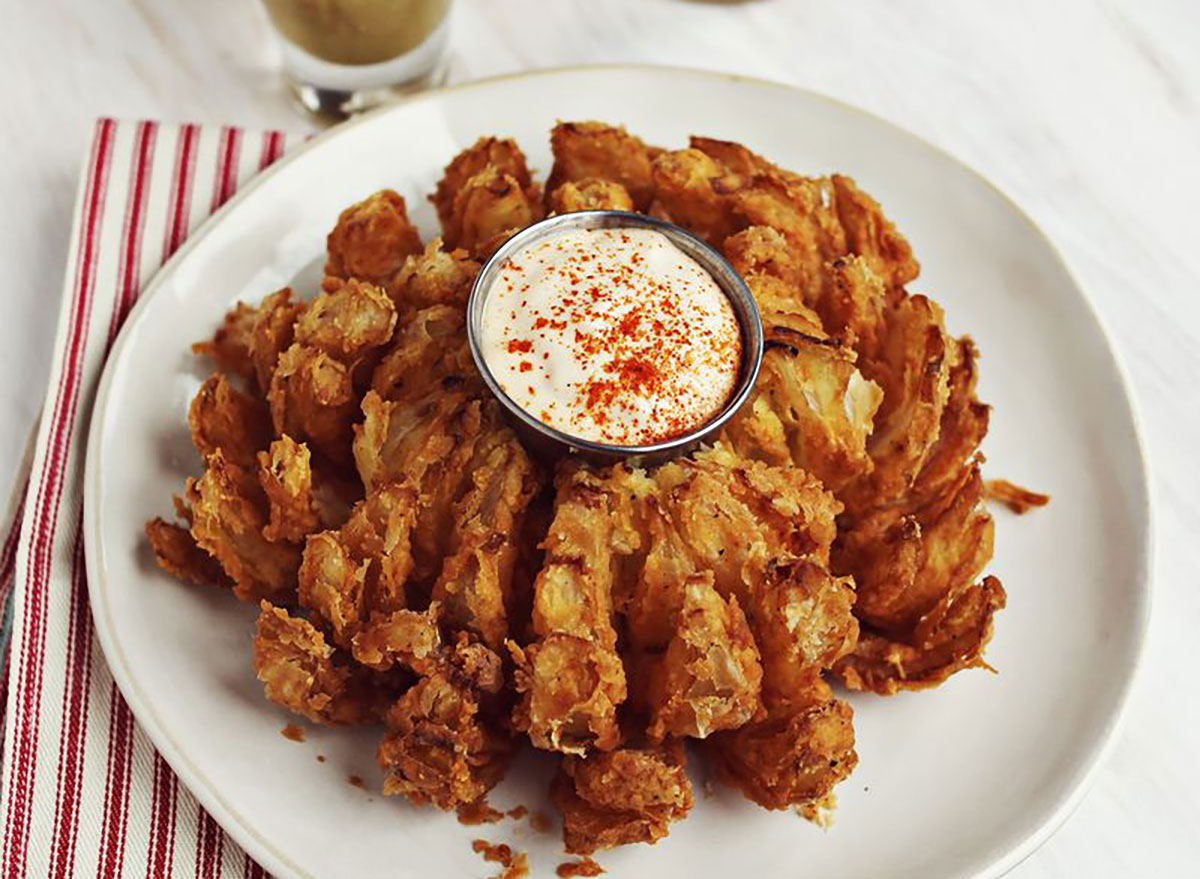 copycat bloomin onion with dip on white plate with red and white striped napkin