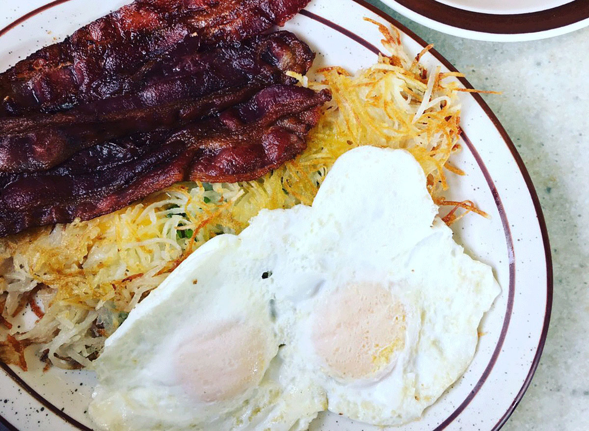eggs, bacon and hash browns on a white plate from moms kitchen
