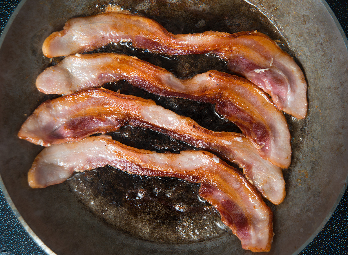 https://www.eatthis.com/wp-content/uploads/sites/4/2019/10/four-pieces-bacon-cooking.jpg