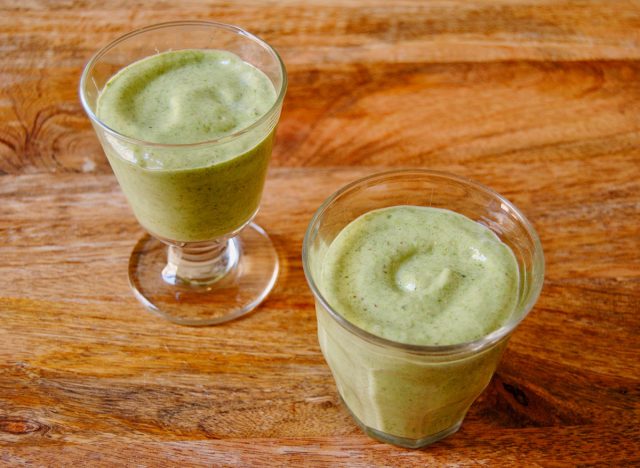 green smoothie in two glasses on a wooden surface