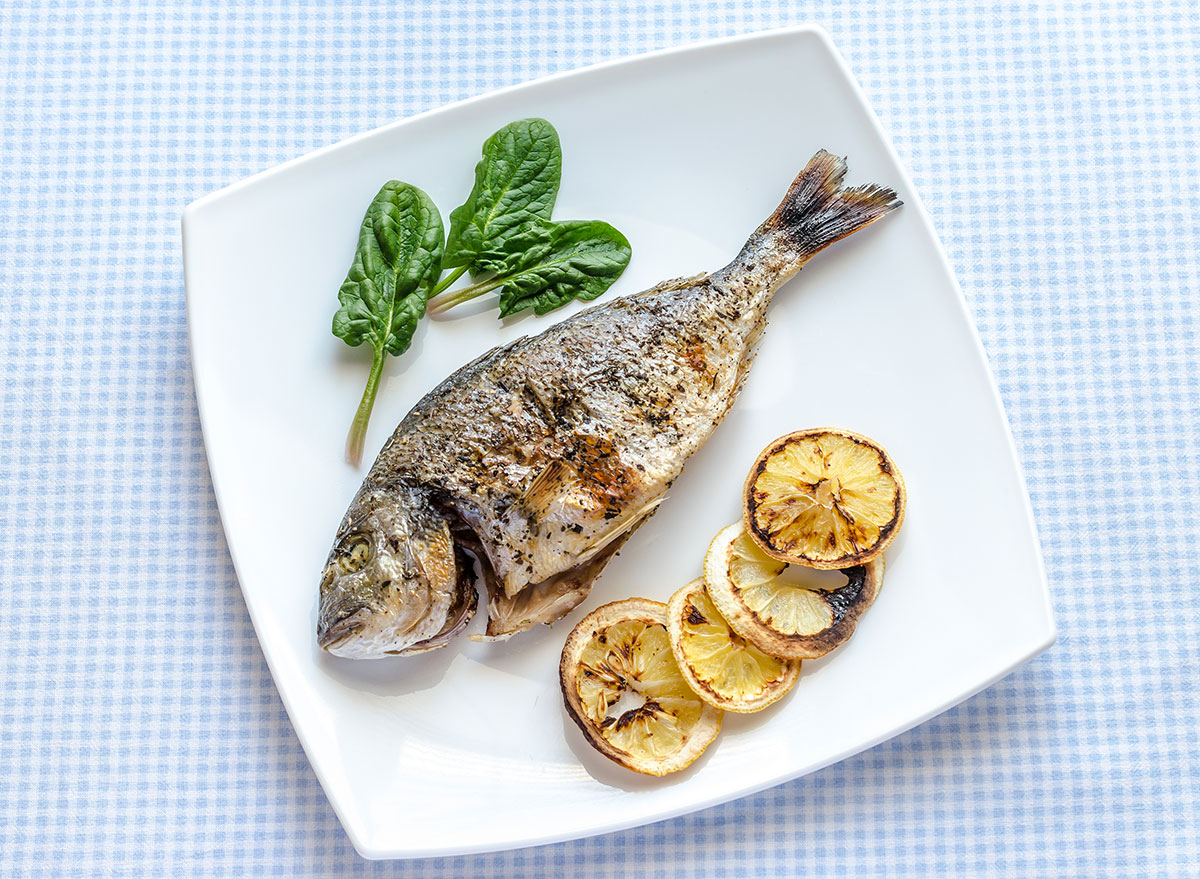 Grilled fish with lemon slices also grilled on a plate