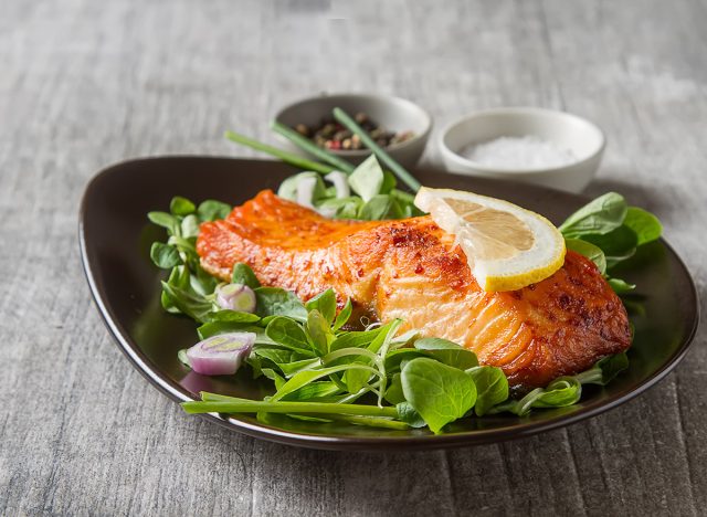 grilled salmon on a bed of spinach topped with a lemon