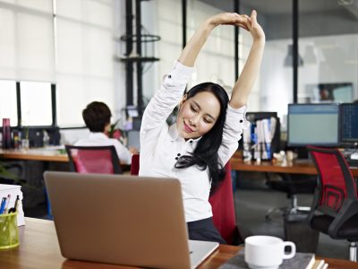 businesswoman looking at work on laptop computer with satisfaction and stretching arms in the air