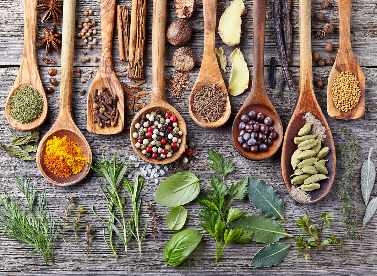 herbs and spices on wooden spoons and wooden surface