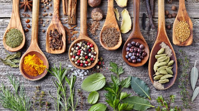 herbs and spices on wooden spoons and wooden surface