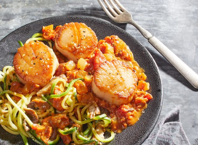 keto thai curry with scallops, zucchini noodles, and shiitake mushrooms on a gray plate with fork