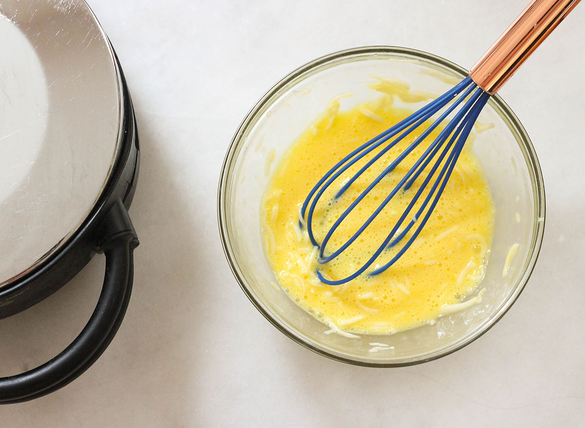 Whisking eggs and cheese together to make keto waffles