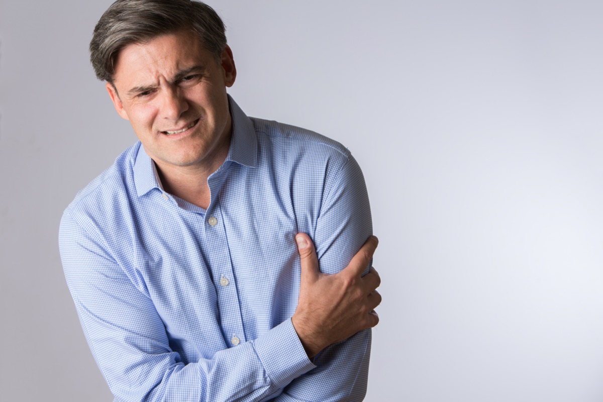 Mature Man Clutching Arm As Warning Of Heart Attack