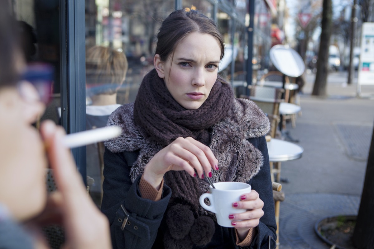 Woman looking displeased at a man smoking outdoor