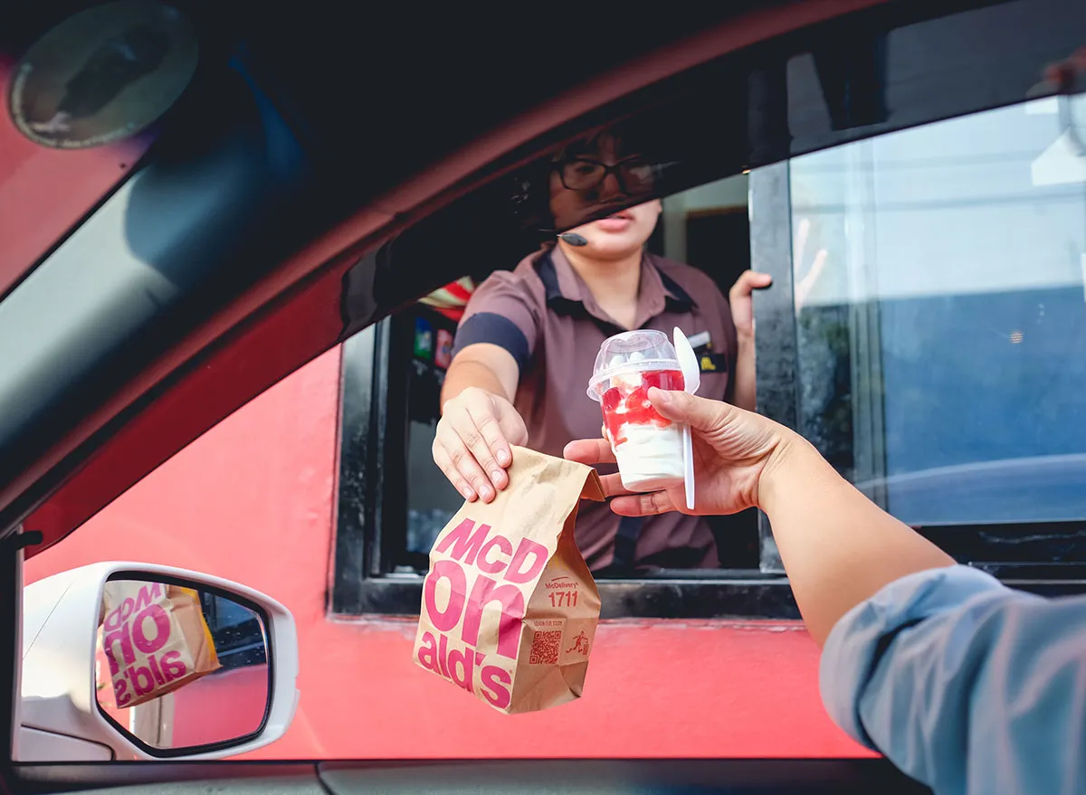 McDonald's employee handing customer food through the drive thru window