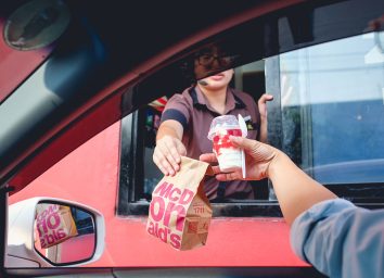 McDonald's employee handing customer food through the drive thru window