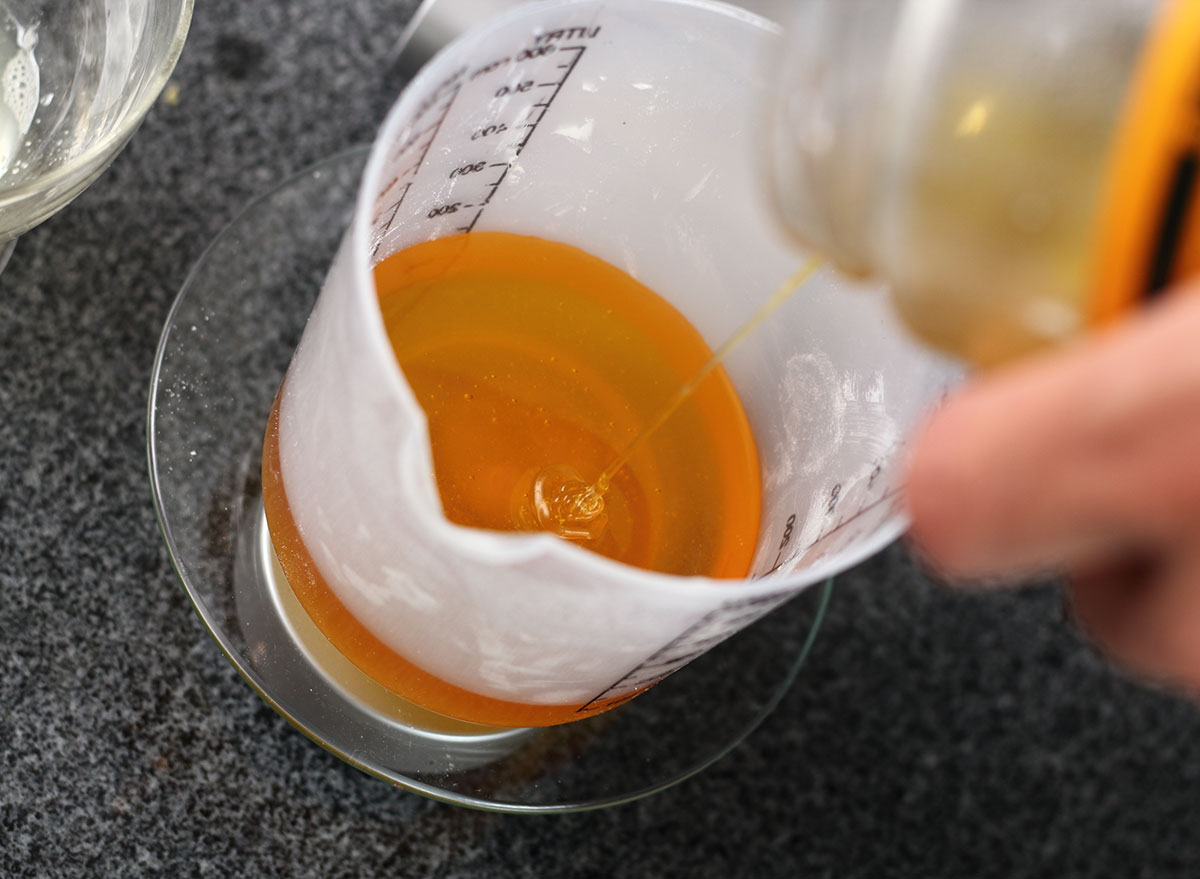 Measuring out honey in a measuring cup