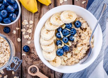 oatmeal with banana and blueberries in a white bowl on wood