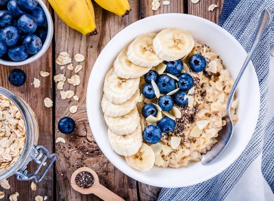 oatmeal with banana and blueberries in a white bowl on wood